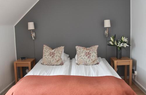 a bed with two pillows and a vase of flowers at Akademihotellet in Uppsala