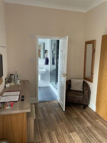 a room with a desk and a chair and a bathroom at The Claymore Guest House in Pitlochry