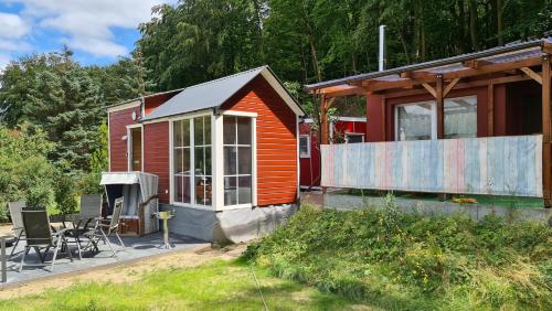 a small red house with a patio and a house at Tiny House Strandwagen mit Terrasse in Ahlbeck