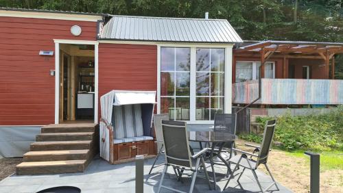 Casa pequeña con patio con mesa y sillas en Tiny House Strandwagen mit Terrasse en Ahlbeck