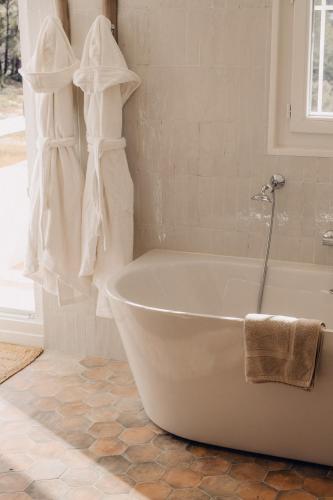 La salle de bains est pourvue d'une baignoire blanche et d'une fenêtre. dans l'établissement Le Clos Serein, au Beausset