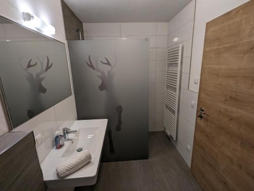 ein Badezimmer mit einem Waschbecken und einer Dusche mit Hirschen an der Wand in der Unterkunft Appartements Gotthardt in Flachau
