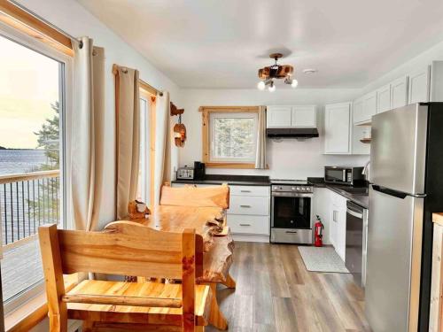 a kitchen with a table and a stainless steel refrigerator at Sable Point Cottage (Lakeside 7-Person Hot Tub & Outdoor Shower) in Grand River