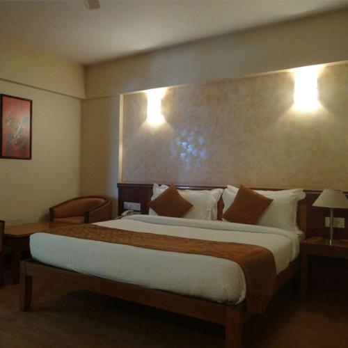 a bedroom with a large bed and two lights on the wall at Hotel Abigail Regency in Shirdi