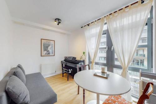 sala de estar con sofá, mesa y piano en Modernistic 2-bedroom flat in Shadwell, en Londres