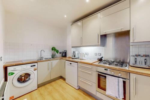 eine Küche mit weißen Schränken und einer Waschmaschine in der Unterkunft Modernistic 2-bedroom flat in Shadwell in London