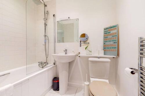 Baño blanco con aseo y lavamanos en Modernistic 2-bedroom flat in Shadwell, en Londres