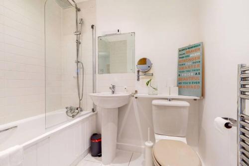 a white bathroom with a toilet and a sink at Modernistic 2-bedroom flat in Shadwell in London