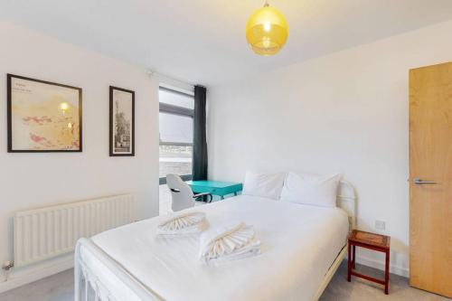 1 dormitorio con cama blanca y mesa en Modernistic 2-bedroom flat in Shadwell, en Londres