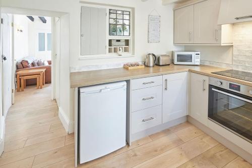 a kitchen with white cabinets and white appliances at Host & Stay - Rose Cottage, Pickering in Pickering