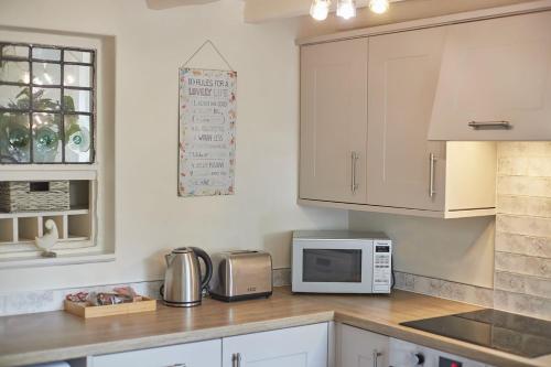 une cuisine avec des armoires blanches et un micro-ondes dans l'établissement Host & Stay - Rose Cottage, Pickering, à Pickering