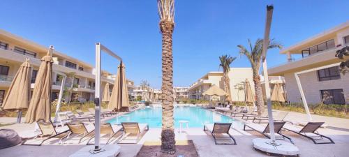 - une piscine avec des chaises et des palmiers dans un complexe dans l'établissement Modern 1-Bedroom Apartment in G-Cribs, El Gouna, pool access, à Hurghada