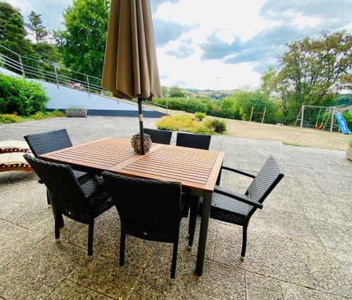 una mesa de madera con sillas y una sombrilla en Villa Schönau, en Bad Münstereifel