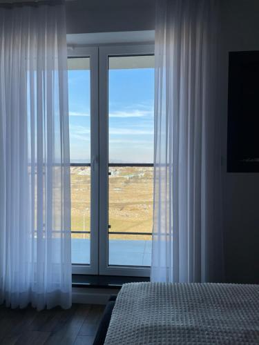 a bedroom with a large window with white curtains at No 59 Apartament in Nowy Targ