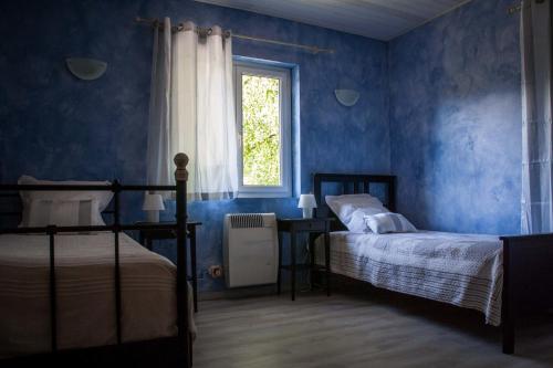 ein blaues Schlafzimmer mit 2 Betten und einem Fenster in der Unterkunft Chambres d'Hôtes L'Orée des Bois in Lacrouzette