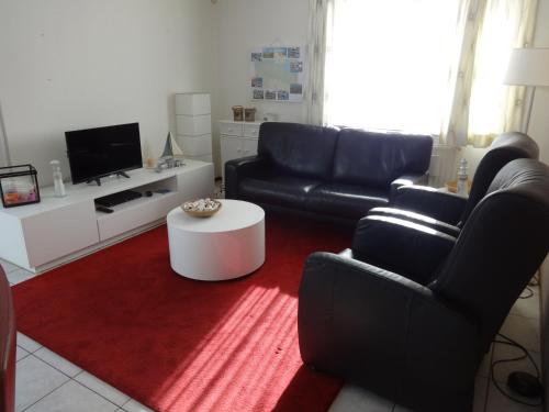 a living room with two black leather chairs and a red rug at Kustverhuur, Park Scheldeveste, Schelde 220 in Breskens
