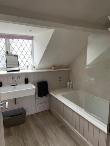 a white bathroom with a tub and a sink at The Old Coach House at BYRE HOUSE 