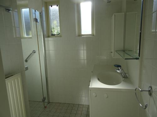 een witte badkamer met een wastafel en een douche bij Kustverhuur, Park Scheldeveste, Schelde 220 in Breskens