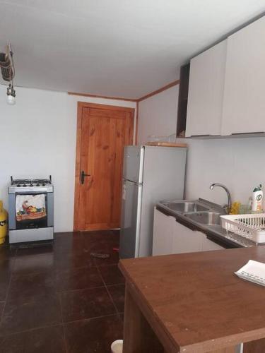 eine Küche mit Kühlschrank, Spüle und Herd in der Unterkunft Cabaña de campo en Pirque in Pirque