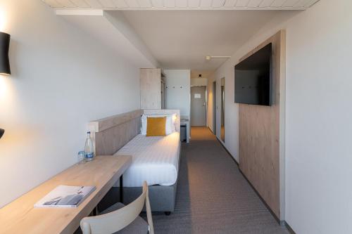 a room with a bed and a desk and a tv at Victoria Hotel & Residence in Villars-sur-Ollon