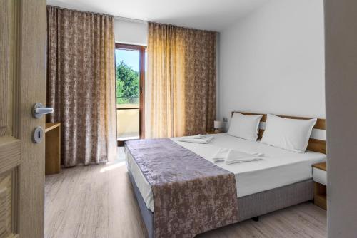 a bedroom with a bed and a large window at Lily Beach Resort in Sozopol