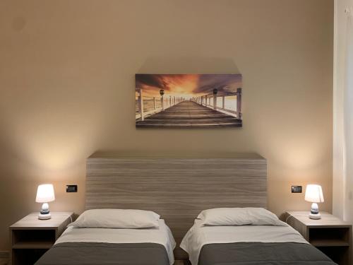 two beds in a room with a painting of a pier at Villa Anna GuestHouse in Brindisi