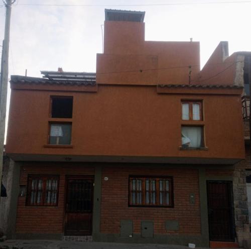 ein altes orangefarbenes Backsteingebäude mit Fenstern in der Unterkunft Hostal Tía Dora in San Salvador de Jujuy