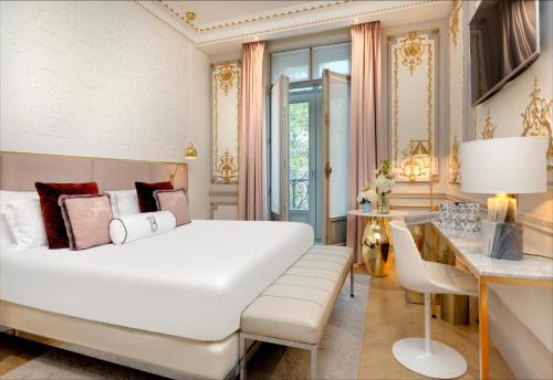 a bedroom with a large white bed and a desk at Hotel Bowmann in Paris