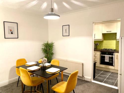 a dining room with a table and yellow chairs at Rochester Townhouse with parking in Strood