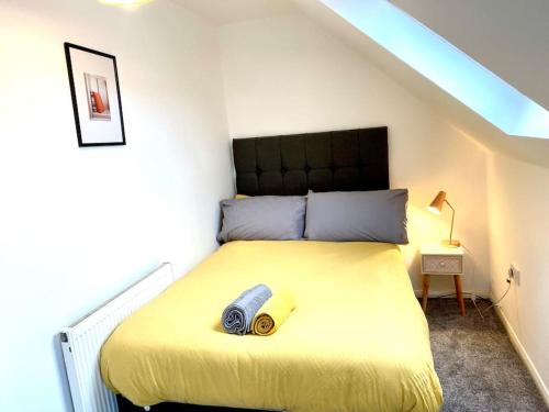 ein Schlafzimmer mit einem großen gelben Bett im Dachgeschoss in der Unterkunft Rochester Townhouse with parking in Strood