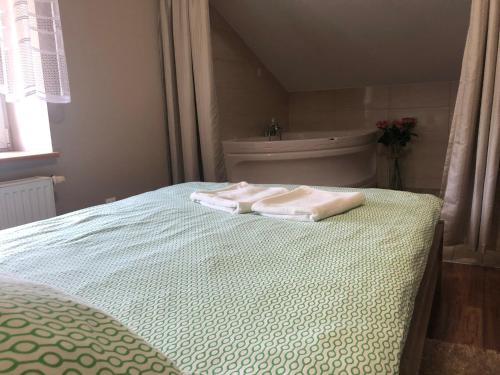 a bed with two towels on it with a bath tub at Piątka noclegi- Łódź in Łódź
