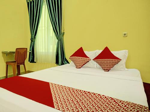 um quarto com uma cama com almofadas vermelhas em OYO 92293 Pahala Syariah Residence em Perabumulih