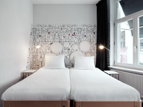 a bedroom with a large bed with white sheets at MABI City Centre in Maastricht