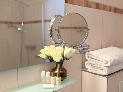 a bathroom with a vase of flowers and a mirror at Hotel Martin am Dom in Bamberg