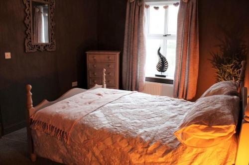 a bedroom with a bed with a dresser and a window at Caterpillar Cottage, tucked away in Kelbrook in Kelbrook