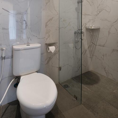 a bathroom with a toilet and a glass shower at The Risman Hotel At Jakarta Airport CBC in Tangerang