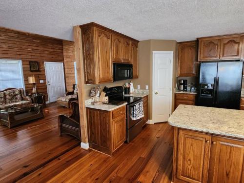 a kitchen with wooden floors and a kitchen with a black refrigerator at 8. Beautiful secluded creek front lodge in Guntersville