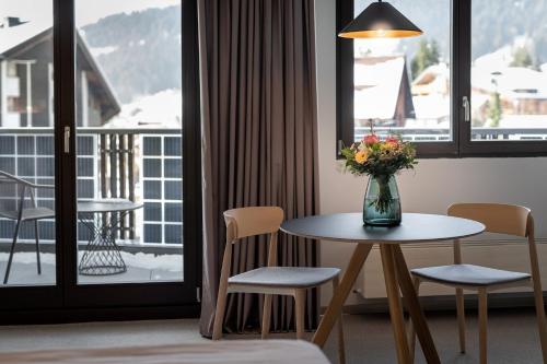a room with a table and chairs and a balcony at Victoria Hotel & Residence in Villars-sur-Ollon