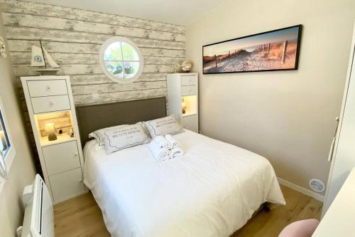 een slaapkamer met een wit bed en een raam bij Cabane du Pêcheur, maison avec extérieur in Le Crotoy