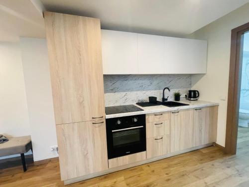 a kitchen with white cabinets and a black oven at Alanta Apartments Easy Kaunas in Kaunas