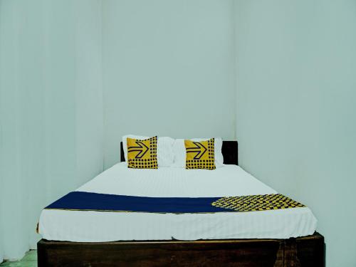 Bett in einem Zimmer mit einer weißen Wand in der Unterkunft SPOT ON 92301 Penginapan Indola 