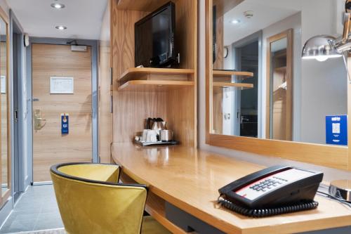 a room with a desk with a telephone and a mirror at Park Inn by Radisson Cardiff City Centre in Cardiff