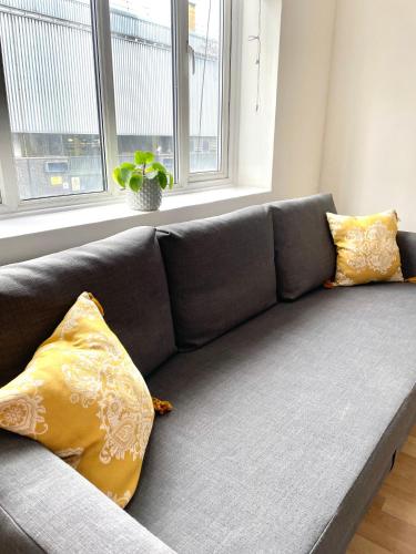 a gray couch with yellow pillows in a living room at 2 bedroom near Euston, King's Cross in London