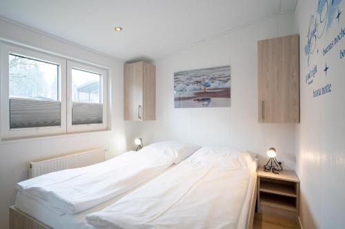 1 Schlafzimmer mit einem großen weißen Bett und 2 Fenstern in der Unterkunft Ferienhaus "Möwennest" in Scharbeutz