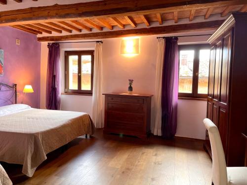 a bedroom with a bed and two windows at La Dimora nel Corso in Montepulciano