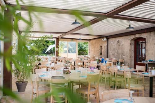 a large room with tables and chairs and plants at Villages Clubs du Soleil - LE REVERDI in Grimaud