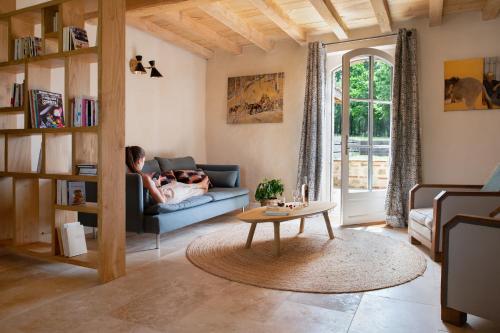 uma mulher deitada num sofá numa sala de estar em L'Héritier, maison climatisée, 12pers avec piscine em Marzens