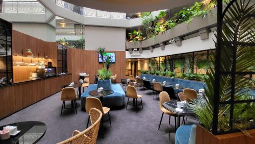 un restaurante con mesas, sillas y plantas en Hôtel Paris Neuilly, en Neuilly-sur-Seine