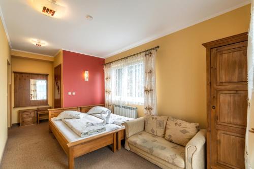 Cette chambre comprend un lit, un canapé et une fenêtre. dans l'établissement Willa Paula, à Ząb