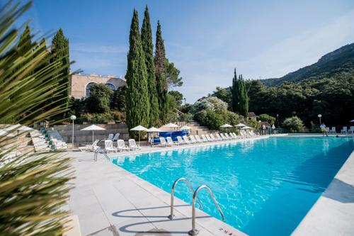 une grande piscine avec des chaises et des arbres dans l'établissement Villages Clubs du Soleil - LE REVERDI, à Grimaud